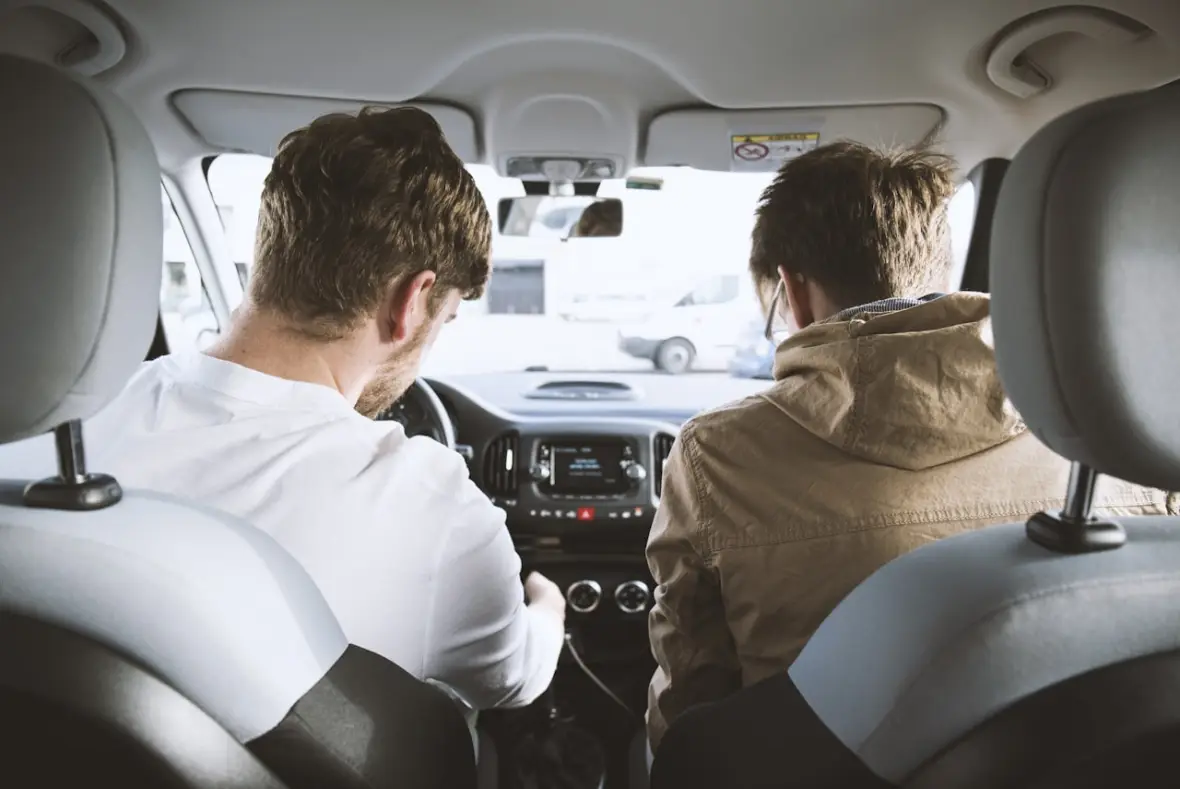 Zwei Personen sitzen vorne im Auto und besprechen während einer ruhigen Fahrt eine Situation